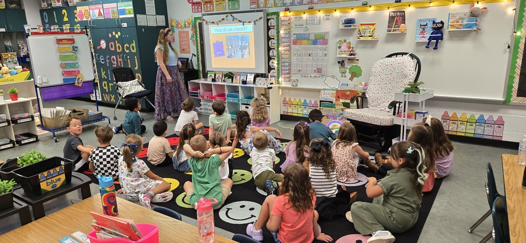 Kindergarten teacher instructing students how to unpack backpacks