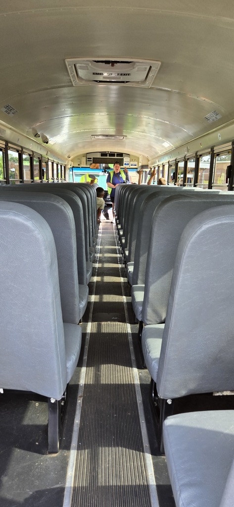 Students on a bus raising their hands to answer a question from the assistant principal