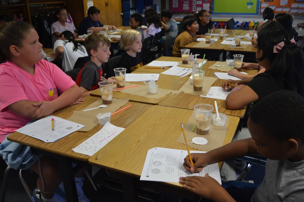 Students are each sitting at their desks with a science paper and a root beer float.