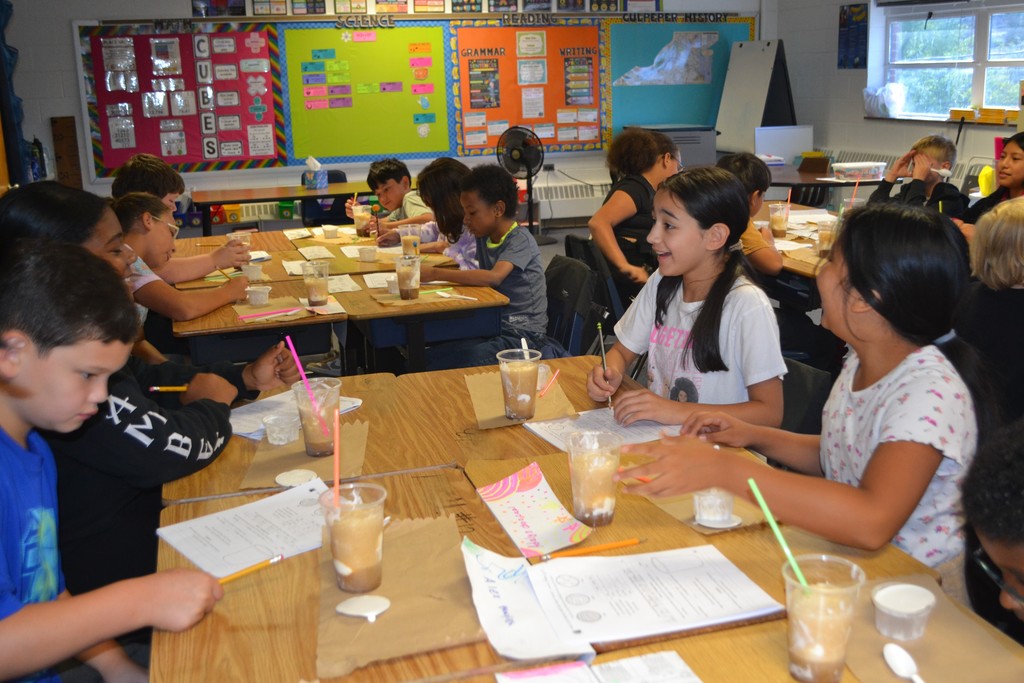 Students are each sitting at their desks with a science paper and a root beer float.