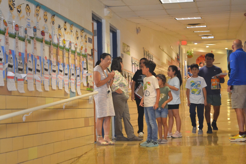 Image contains teachers talking to families during Back to School night in the school hallway.
