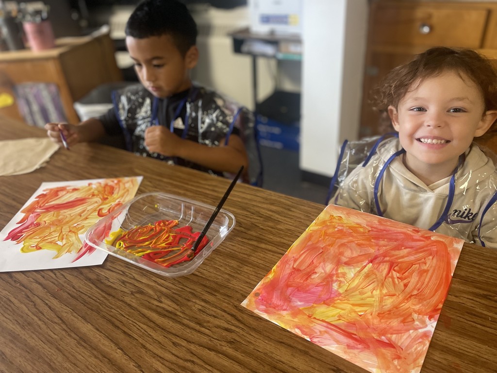 Image contains two young students doing their fall painting artwork in school.