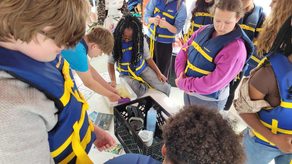 students in life jackets gather around marine life trawled from the James River.