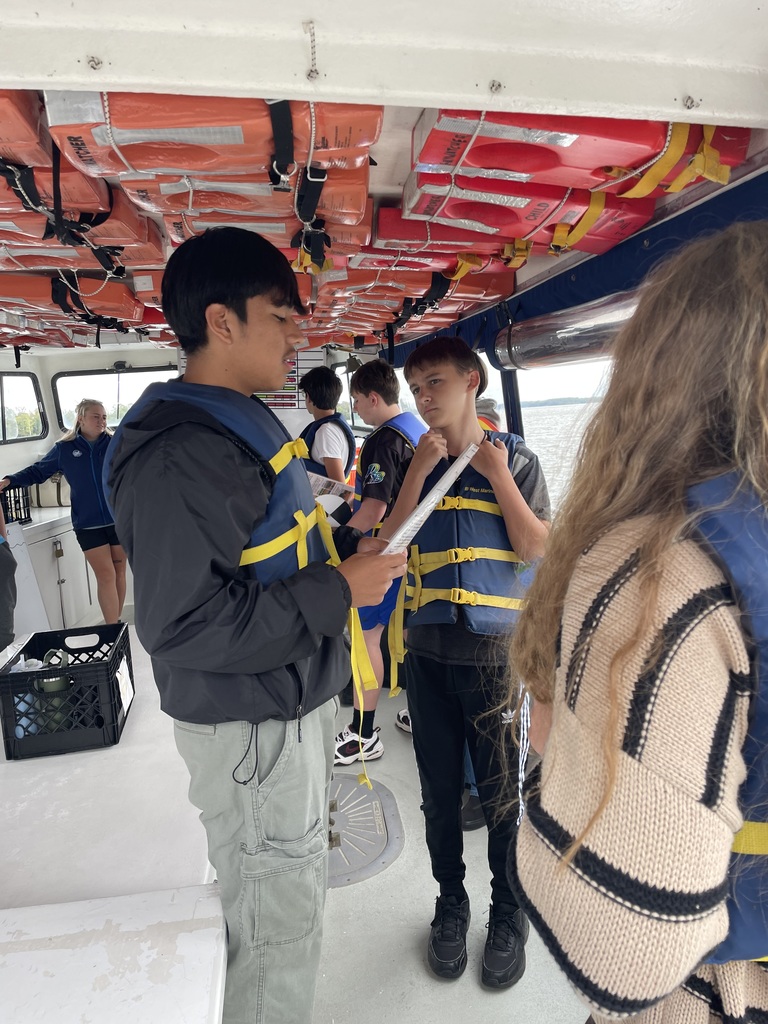 student in life vest reads from paper.
