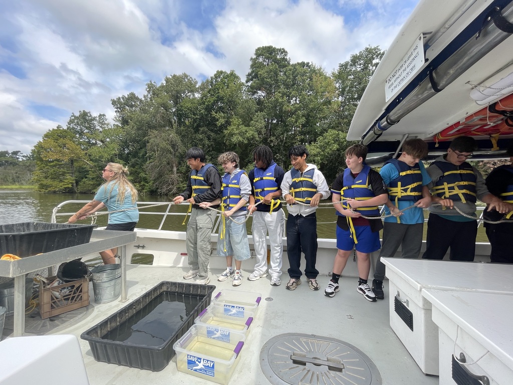 students in life jackets line up to assist in pulling in the trawling nets.