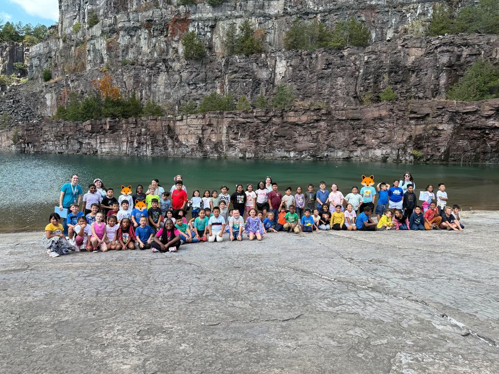 A grade level of students and teachers pose at the rock quarry while on a field trip.