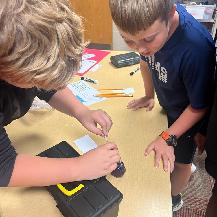 two students smile and look upon a lock box with candy inside 