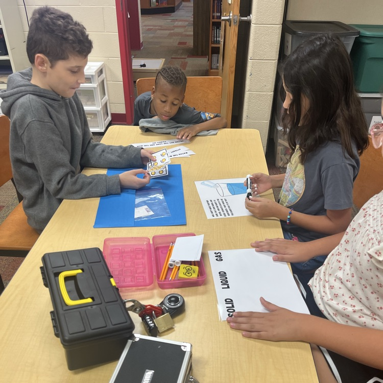 two students organize materials at a table to prepare for a breakout activity 