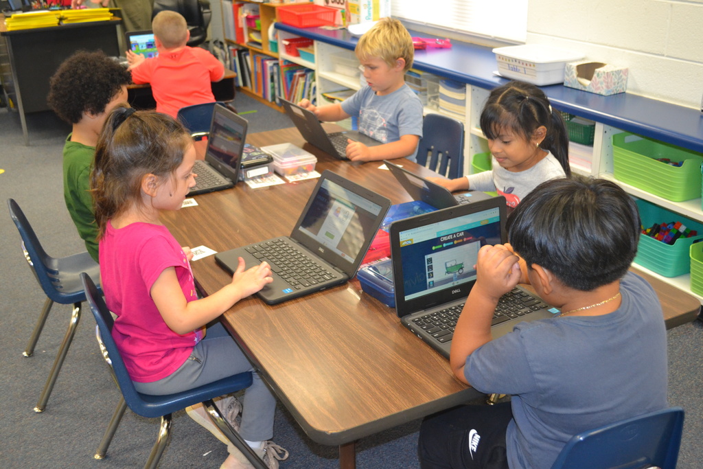Image contains 6 kindergartners each on their chromebook in a classroom.  Each student is learning to use their chromebook.