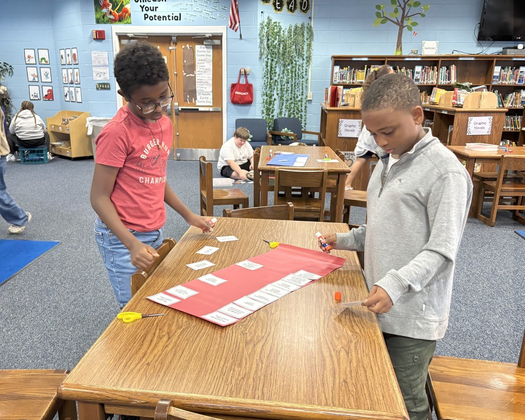 Image contains two boy students working on a Preamble project in the school library at the table.