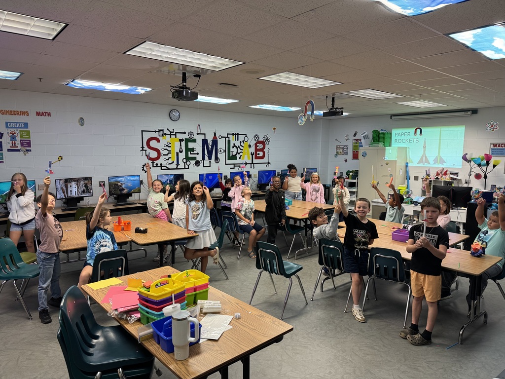Students holding up paper rockets in STEM lab