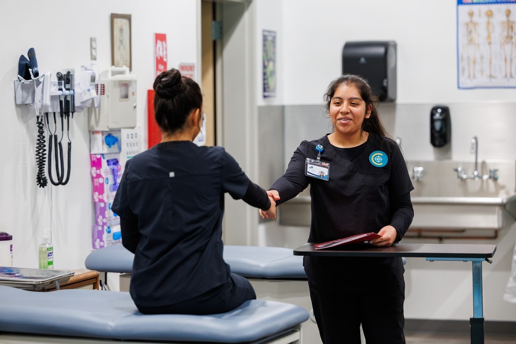 Two CTEC medical assistant students shake hands after completing a rooming exercise, demonstrating professionalism in a clinical setting.