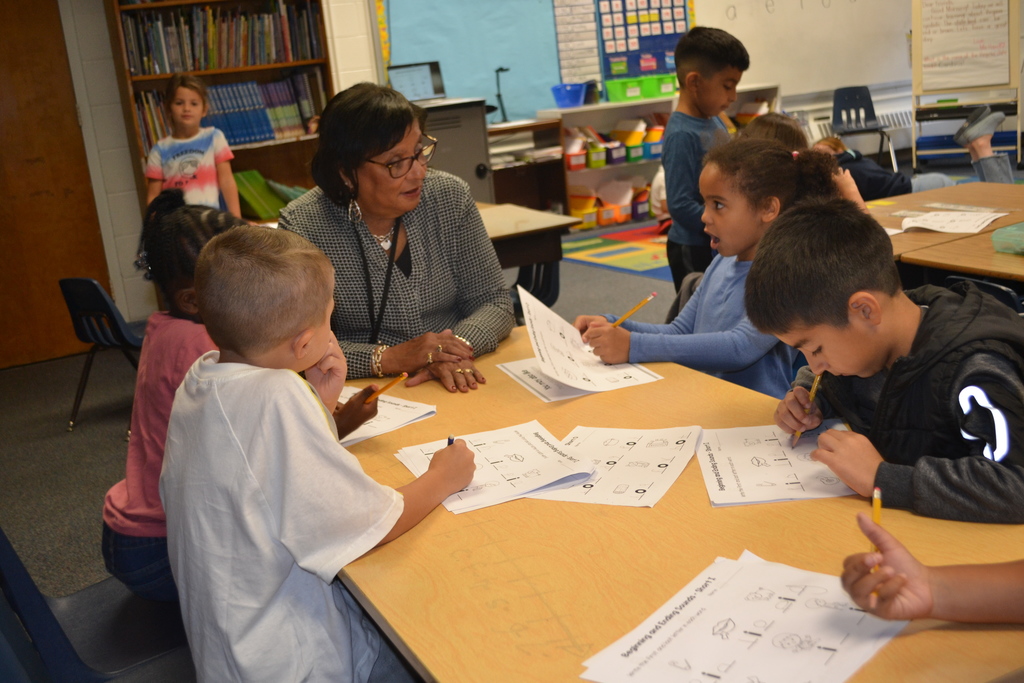 Image contains a teacher working at a table with a small group of students during reading.