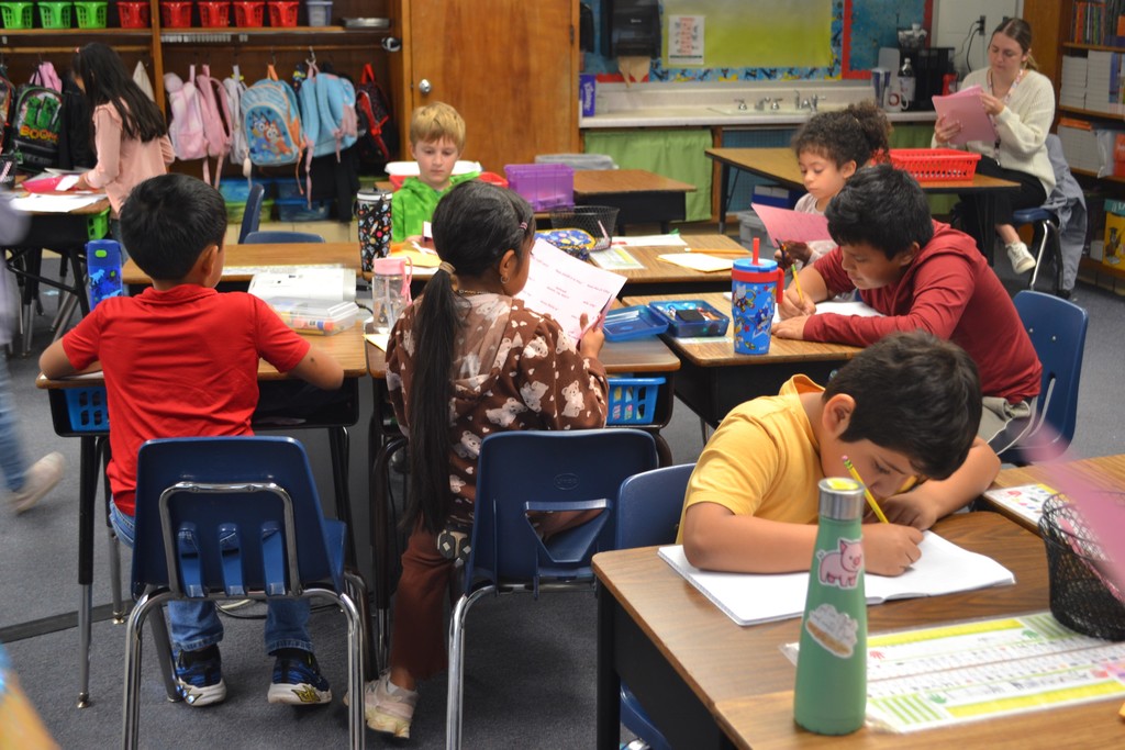 A group of students sitting at their desks working on their language arts assignments in a school classroom.
