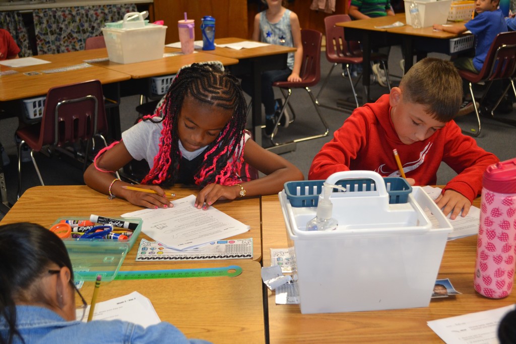 A group of students sitting at their desks working on their language arts assignments in a school classroom.