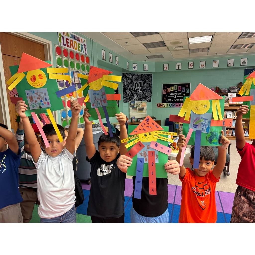 Another group of children proudly raise their scarecrow crafts above their heads.