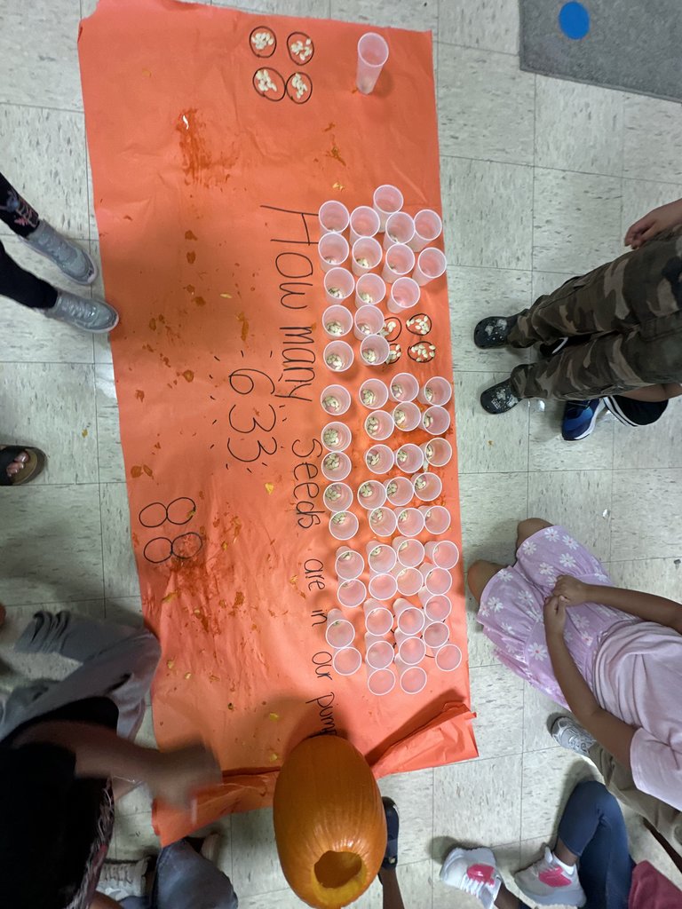 Students posing proudly around the completed chart that shows “633” seeds written on the poster beside the pumpkin