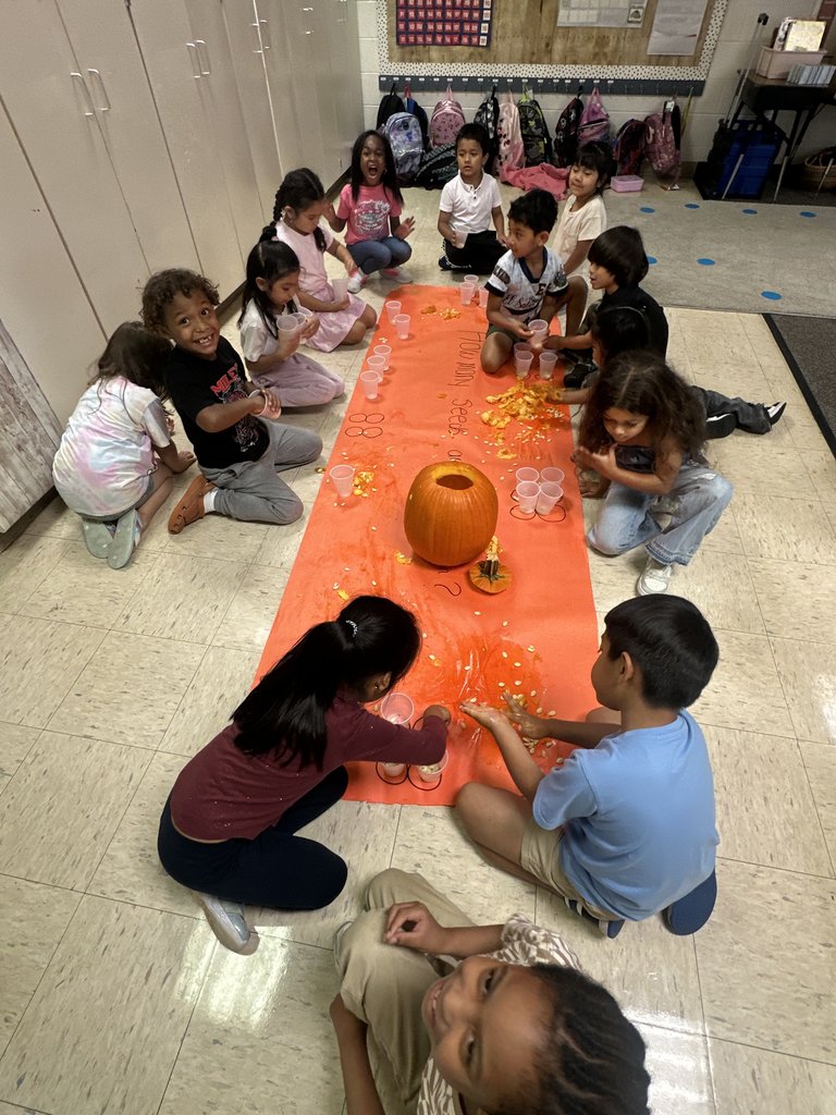 Students laughing and working together while scooping pumpkin seeds into cups during the group activity.