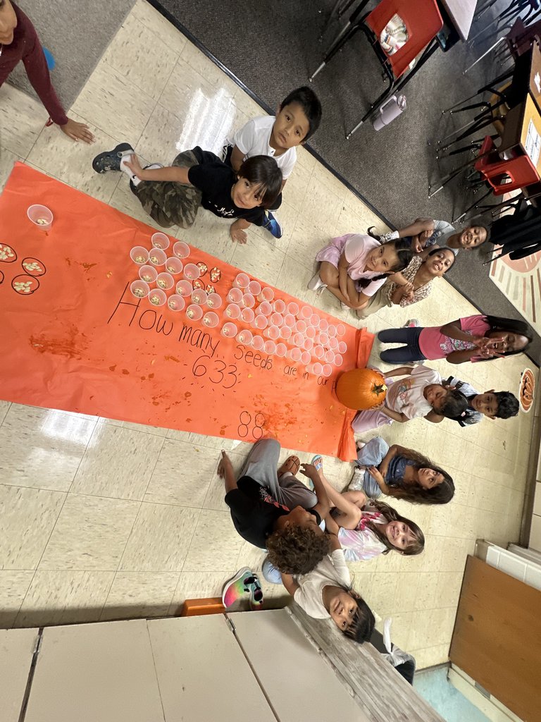Students posing proudly around the completed chart that shows “633” seeds written on the poster beside the pumpkin