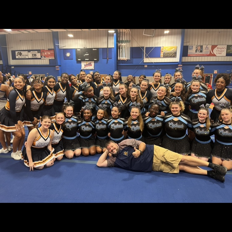 Nobbs laying on mat in front of CCHS and EVHS cheerleaders.