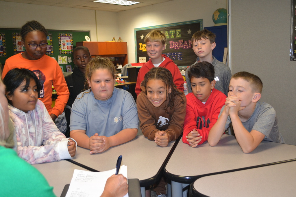 Nine students are eagerly looking as the teacher writes down their ideas during the SCA meeting.