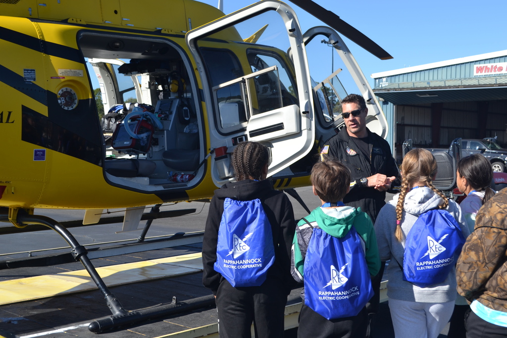 Image contains students listening to a helicopter pilot.
