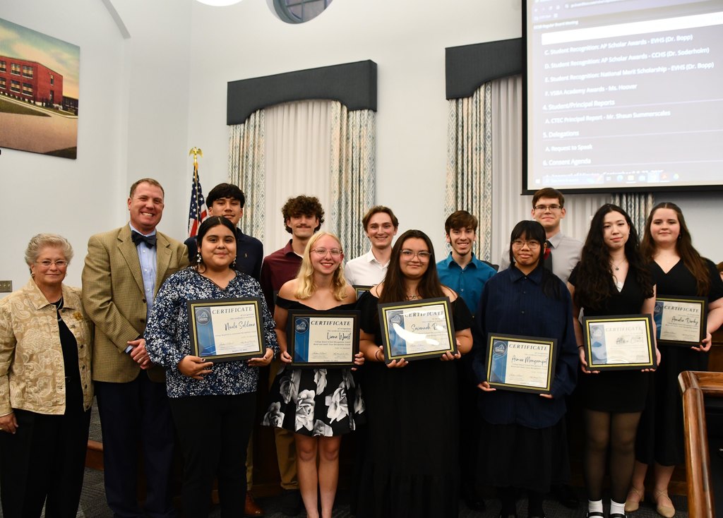 group of eleven students in board room holding certificates with board member and principal standing on the left 
