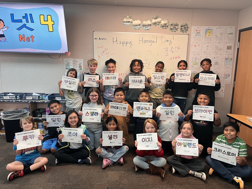 Image contains the whole class holding up their names colored in the Korean alphabet "Happy Hangul Day!"