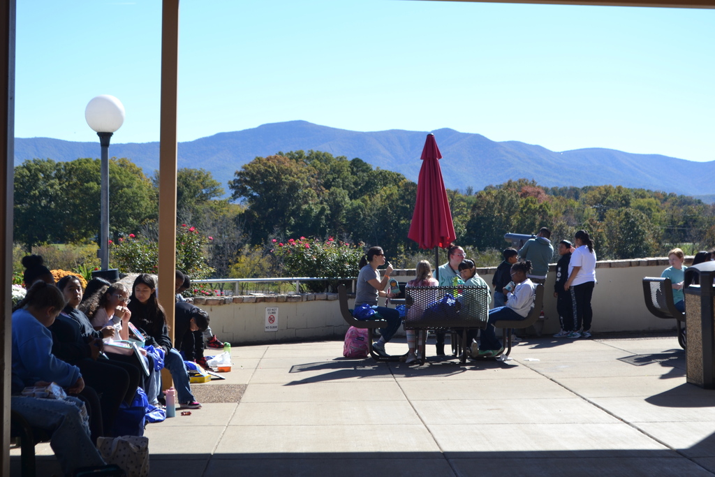 Image contains a class eating at the tables with the Blue Ridge Mtns in the distance.