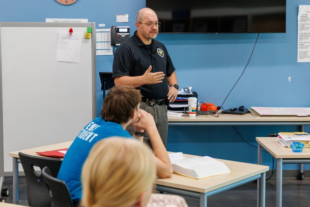 A law enforcement officer speaks to EMT students during a classroom discussion at CTEC, emphasizing key points while students listen attentively.