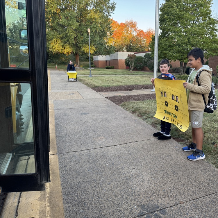 students standing near the bus holding a thank you sign