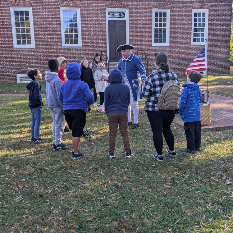 students listening to a man dressed in colonial attire
