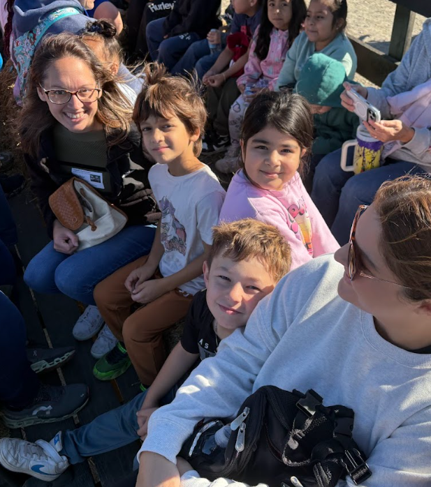 Photo 4: A group of students and chaperones sit closely together on a hayride wagon, smiling at the camera.