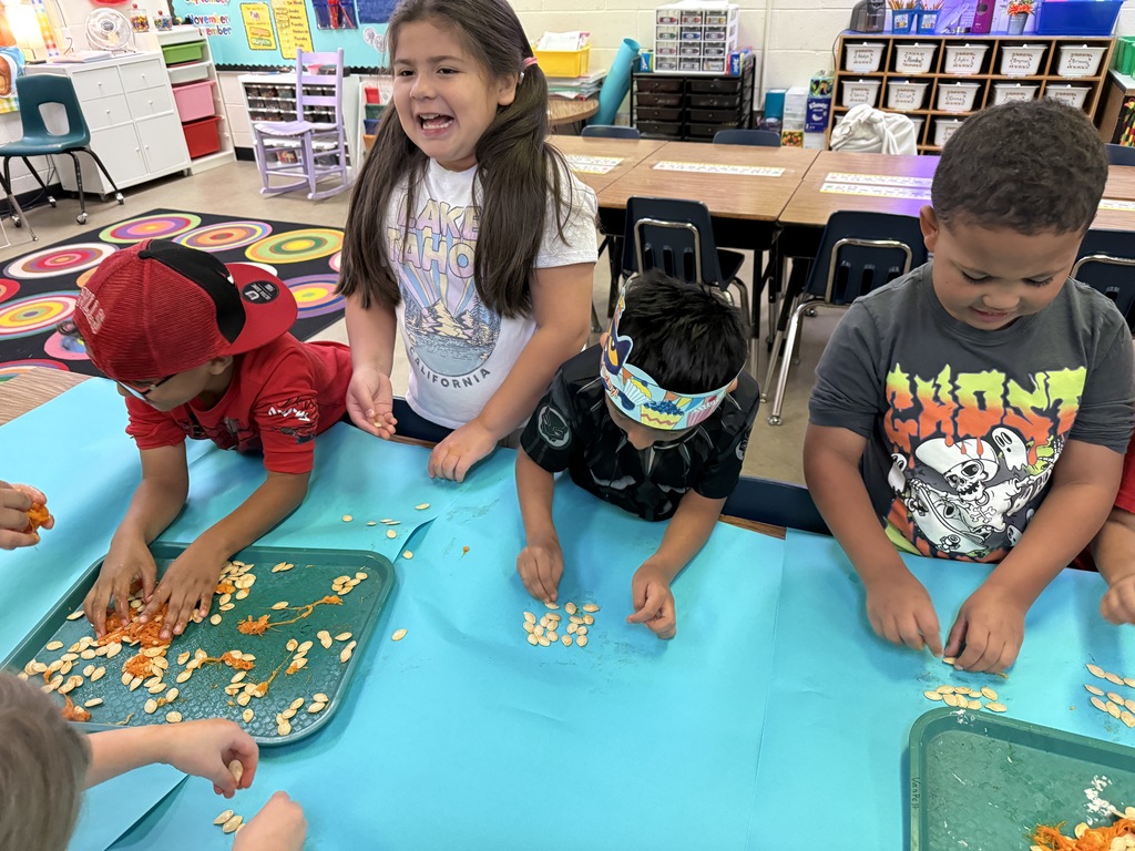 A girl with a bright smile sitting at a table with other students, participating in a group activity.