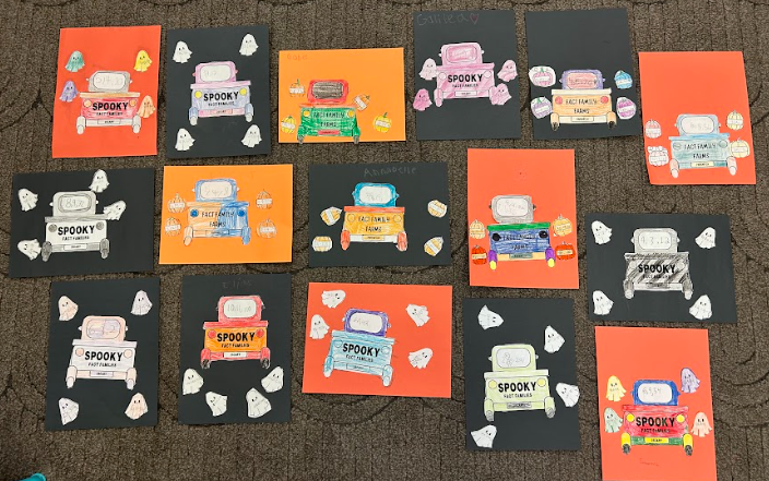 A collection of completed “Spooky Fact Families” projects displayed on the floor. The colorful papers feature Halloween-themed math worksheets decorated with ghosts, candy, and bright backgrounds in orange, black, and red.