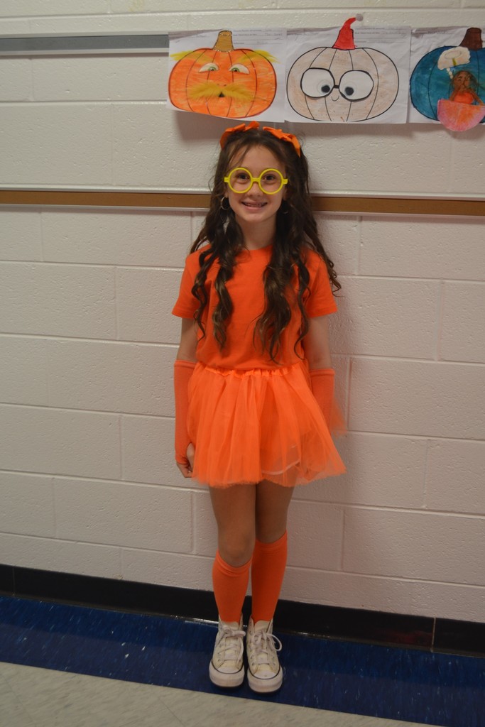 Student dressed in all orange to look like the Lorax poses next to a pumpkin that looks like the Lorax.