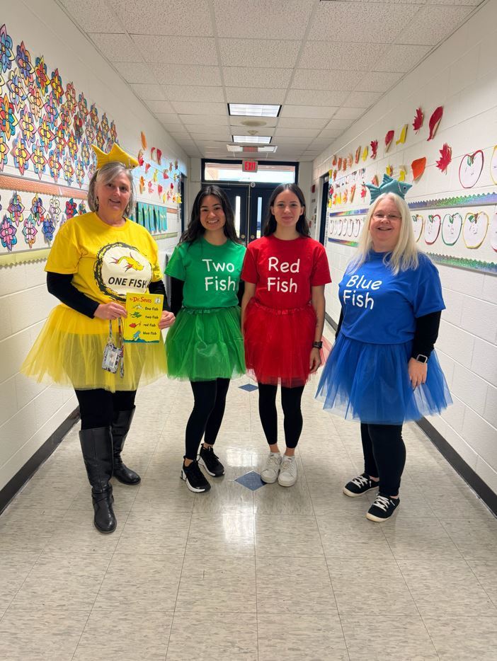4 teachers dressed like the book One Fish, Two Fish, Red Fish, Blue Fish standing in the school hallway