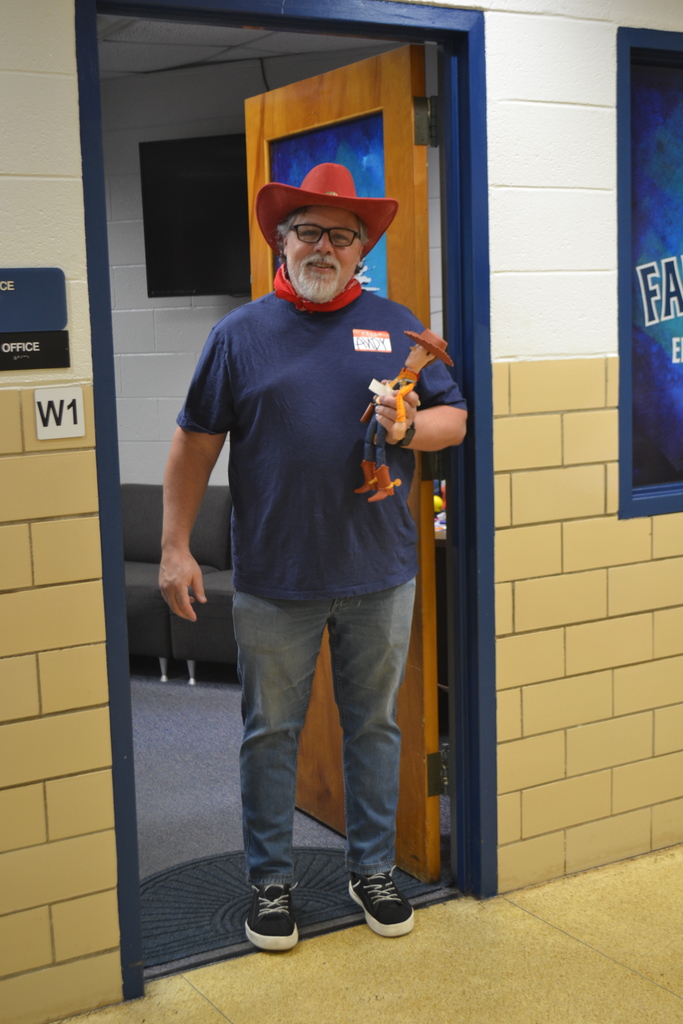 Teacher poses as Andy from Toy Story holding a toy version.