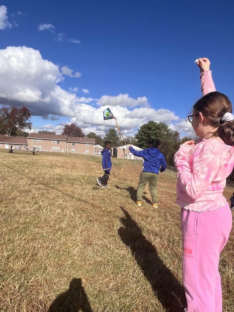 3 students flying kites with smiles on their faces.