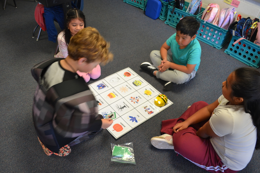 4 students doing a beebot map Halloween theme on the carpet in their classroom.