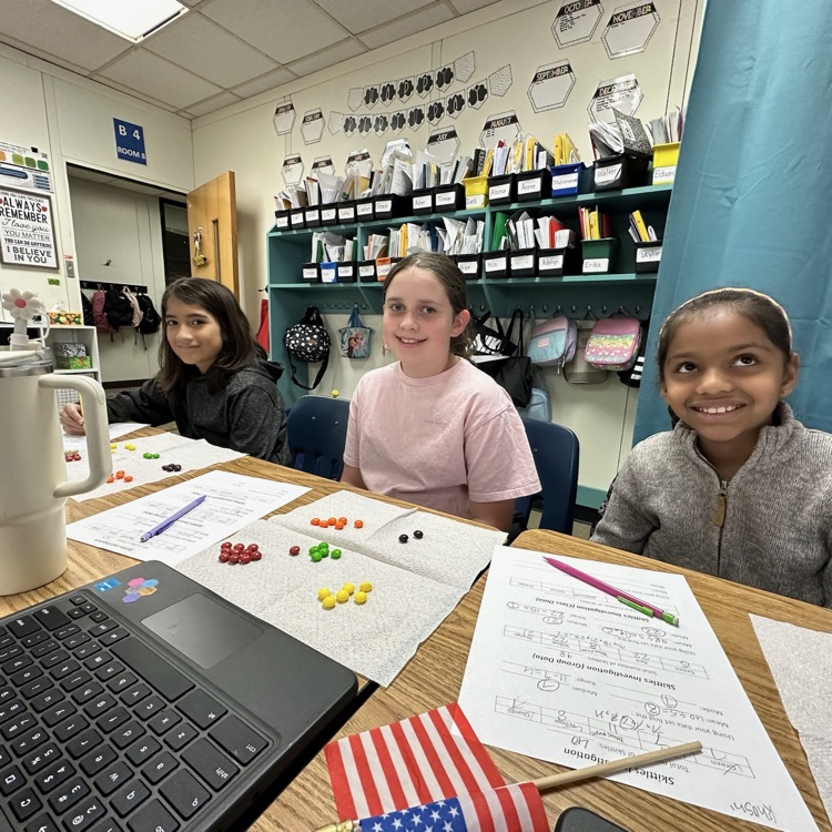 three girls smiling while working with skittles
