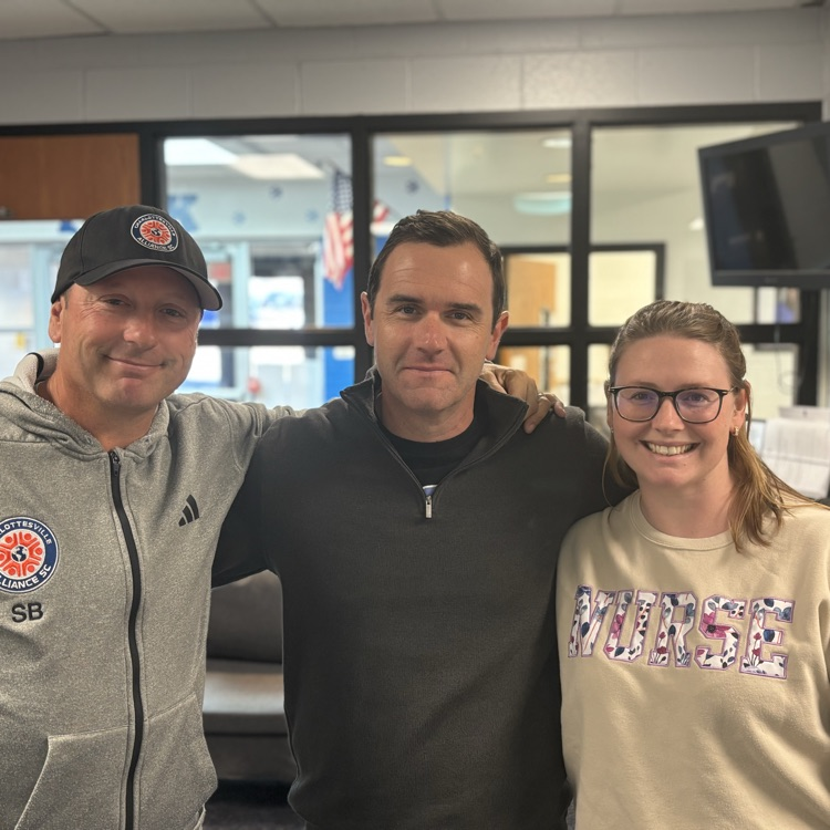 Three adults staring in an office. they are smiling