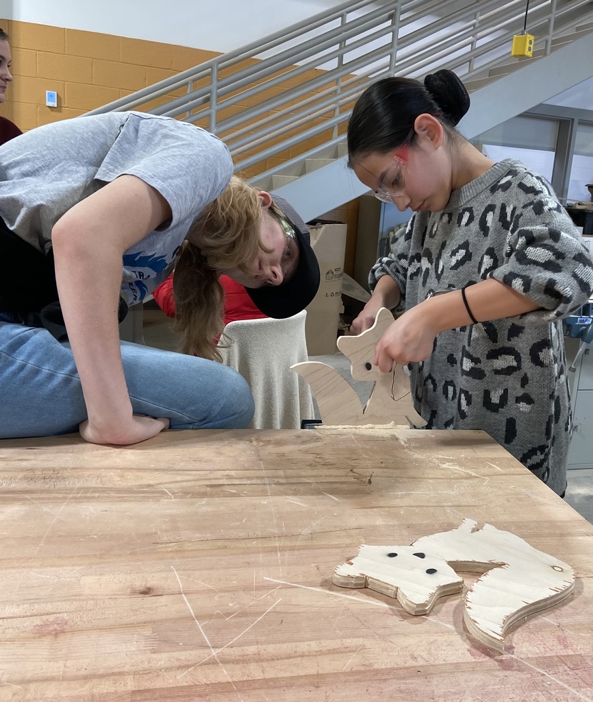 Student is learning carpentry skills from a high school student in a technical class.