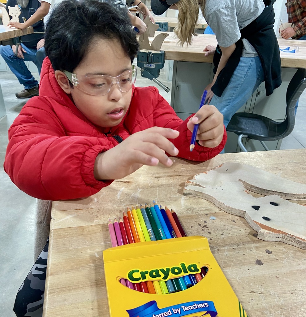 Student wearing protective eyewear is coloring on a fox that was cut out.