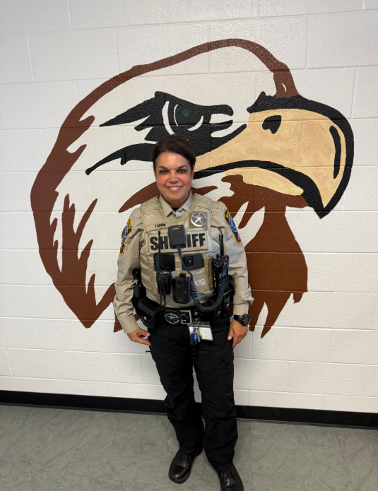 Deputy Thorn in uniform standing in front of a mural of an eagle.