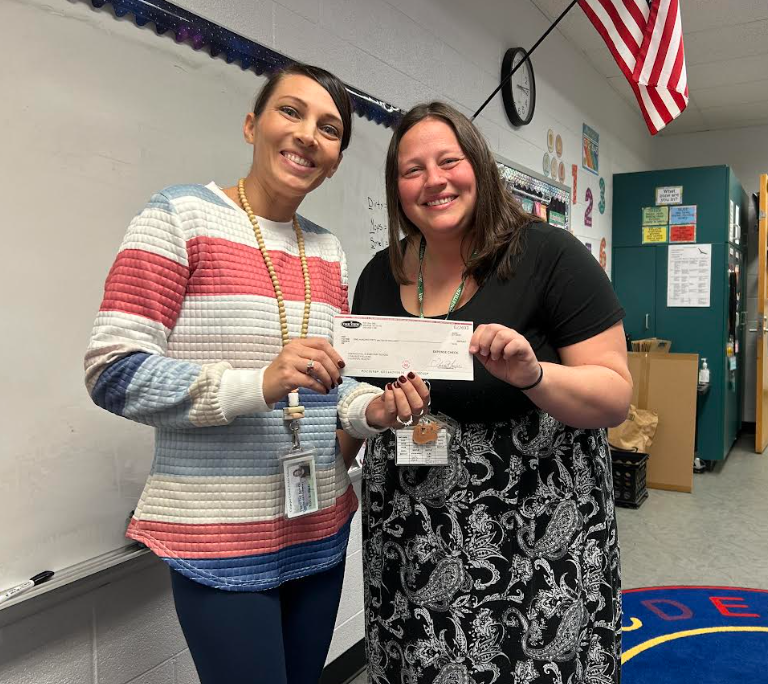 Two teachers holding up a check