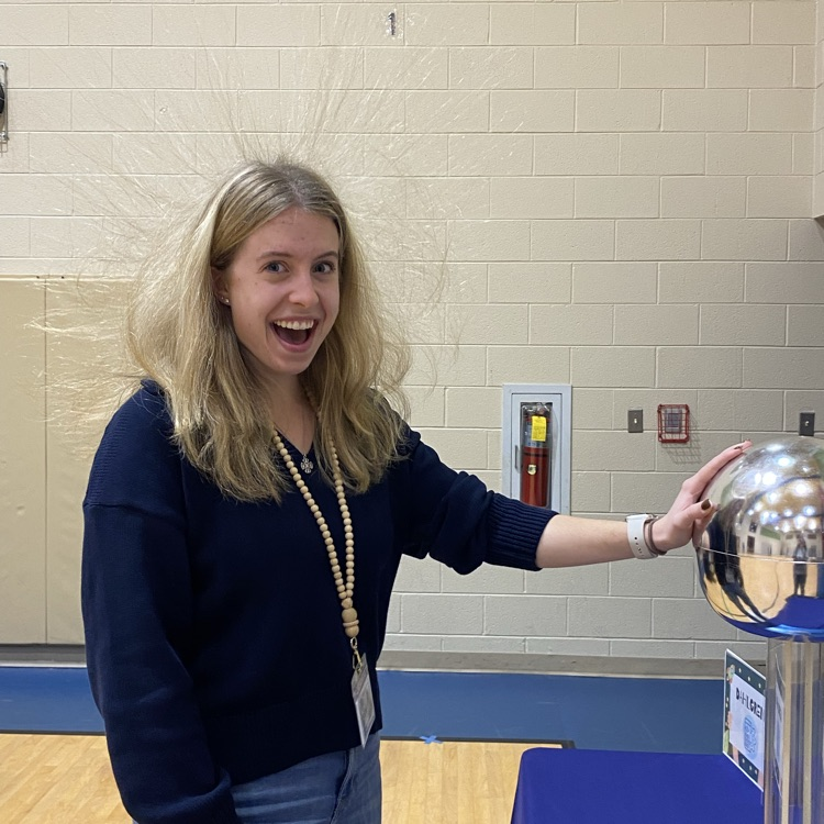 third grade teacher, Mrs. Swope stands by an electric machine with her hair, floating in the air due to the static electricity