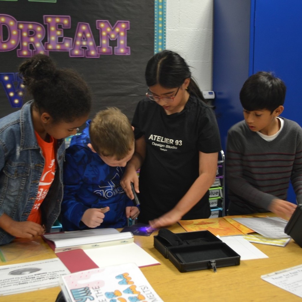 Four students read clues to solve a Breakout in a classroom.