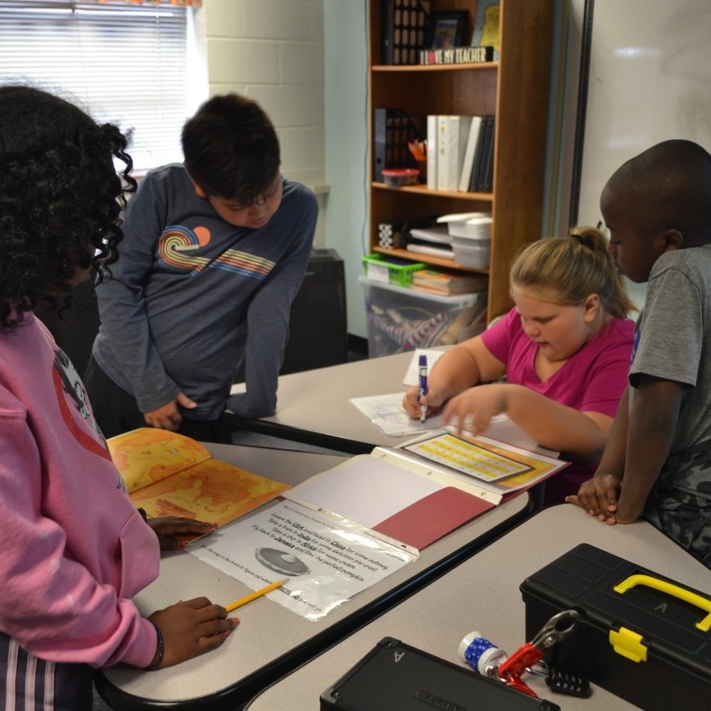 Four students work together to solve a Breakout in a classroom with locks.