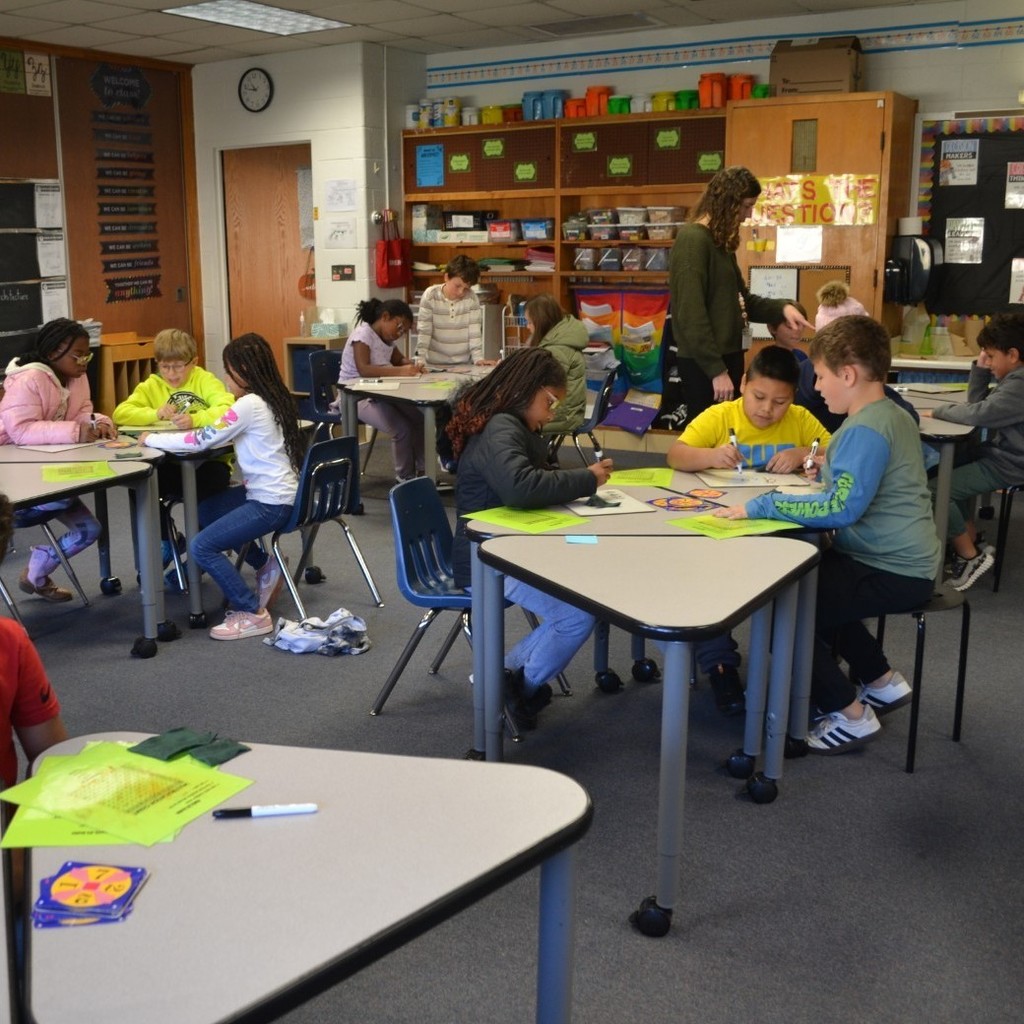 A classroom of students play Math 24 while eating lunch in the classroom.